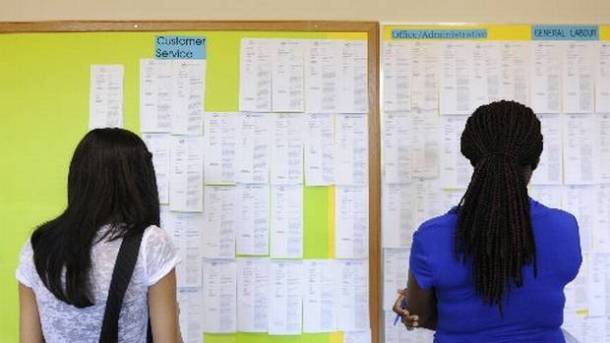 Image of two women looking at job listings on a bullentin board.